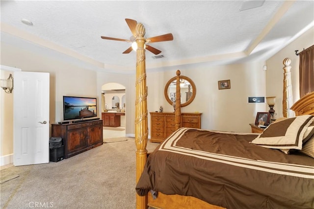 carpeted bedroom featuring ceiling fan, connected bathroom, and a raised ceiling