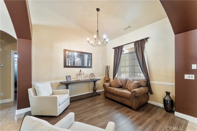 living room with vaulted ceiling, a notable chandelier, and hardwood / wood-style flooring