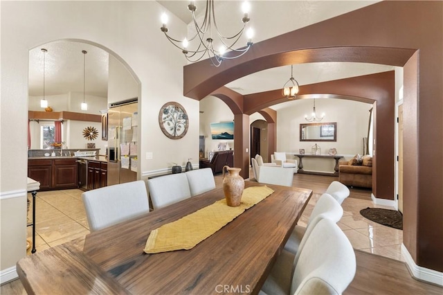 dining space with light tile patterned floors, vaulted ceiling, sink, and an inviting chandelier