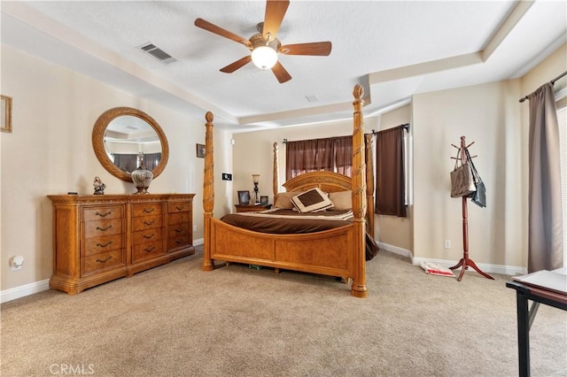 carpeted bedroom with ceiling fan and a tray ceiling