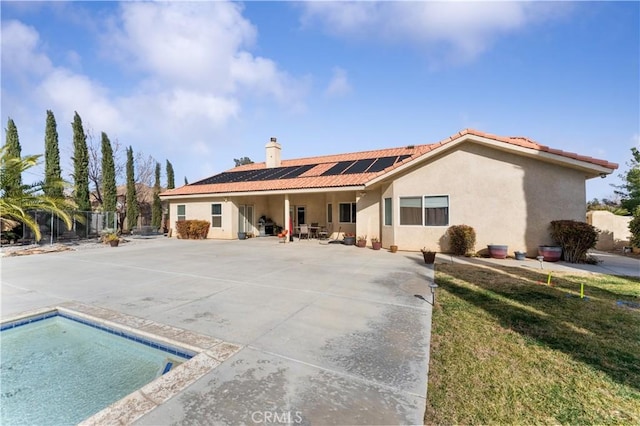 back of property with a lawn, solar panels, and a patio