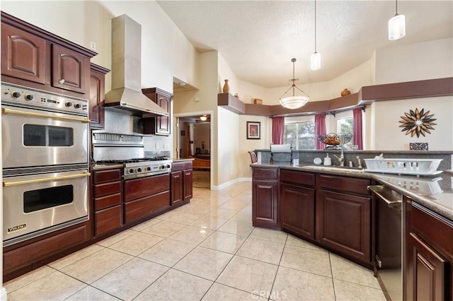 kitchen featuring appliances with stainless steel finishes, decorative light fixtures, wall chimney range hood, sink, and light tile patterned floors