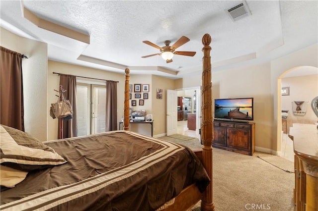 carpeted bedroom featuring ceiling fan, french doors, a tray ceiling, and a textured ceiling