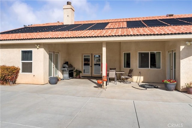 rear view of house with a patio area, french doors, and solar panels