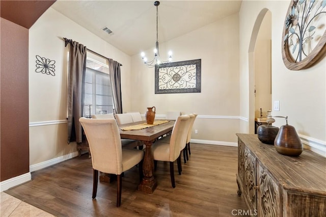 dining area featuring dark hardwood / wood-style flooring, lofted ceiling, and an inviting chandelier