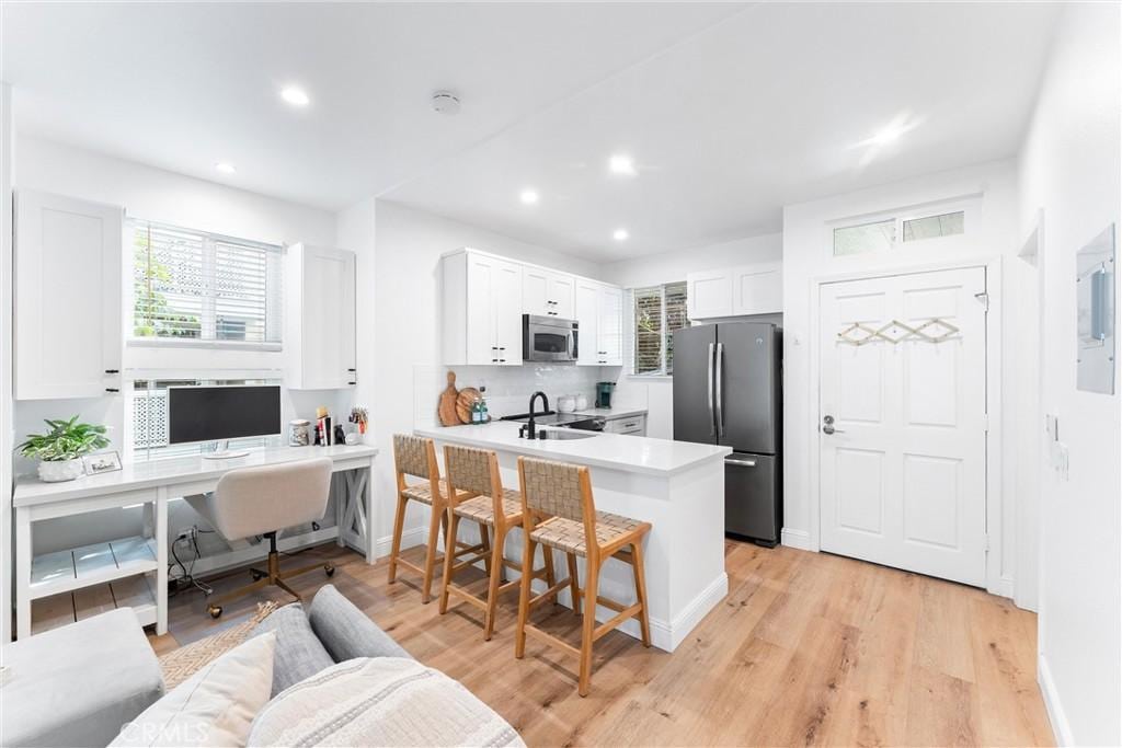 kitchen featuring sink, a breakfast bar area, appliances with stainless steel finishes, kitchen peninsula, and white cabinets