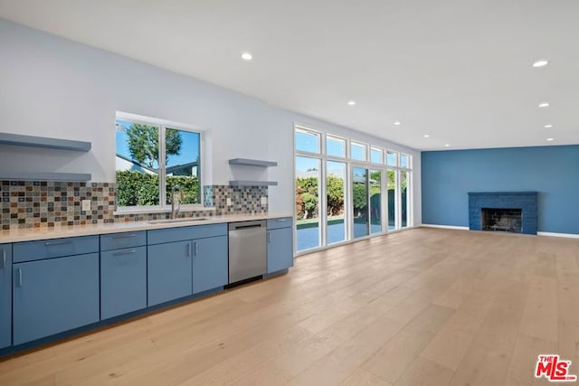 kitchen with a fireplace, dishwasher, decorative backsplash, sink, and light hardwood / wood-style flooring