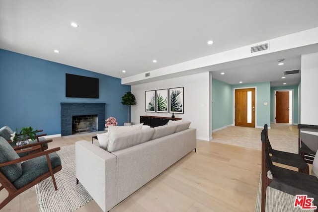 living room featuring light hardwood / wood-style flooring and a stone fireplace