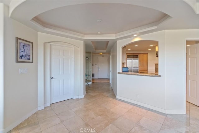 interior space with stainless steel built in fridge, light tile patterned flooring, and a tray ceiling