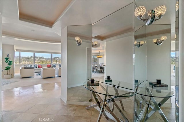 dining room with light tile patterned floors, baseboards, and a tray ceiling