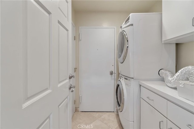 laundry room with cabinets, light tile patterned floors, and stacked washer / drying machine