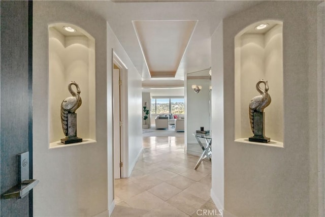 corridor featuring light tile patterned flooring and baseboards