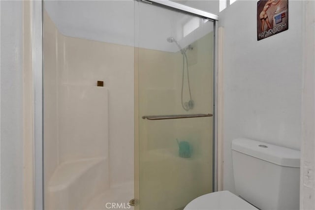 bathroom with toilet and a shower with shower door