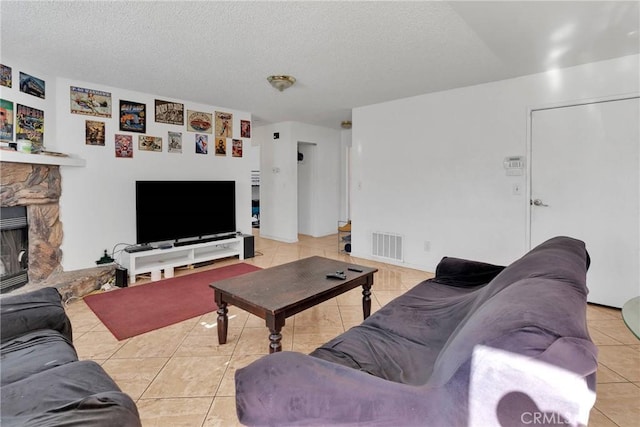 living room featuring a textured ceiling, a stone fireplace, and light tile patterned flooring