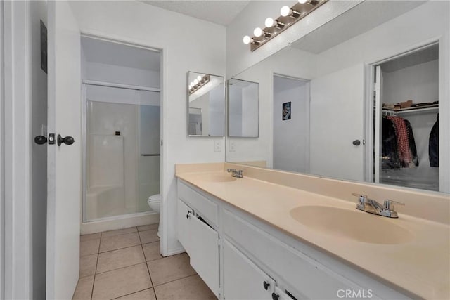 bathroom featuring toilet, a shower, vanity, and tile patterned floors