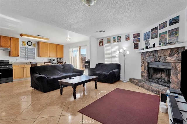 living room with light tile patterned flooring, a stone fireplace, and a textured ceiling