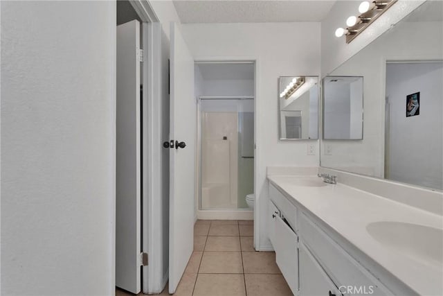 bathroom with tile patterned floors, walk in shower, a textured ceiling, vanity, and toilet