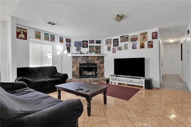 tiled living room featuring a stone fireplace and a textured ceiling