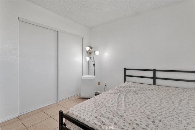 tiled bedroom with a closet and a textured ceiling