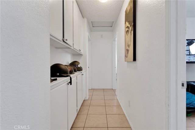 hallway featuring washer / dryer, light tile patterned floors, and a textured ceiling