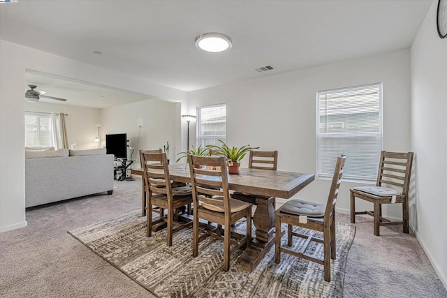 carpeted dining area with ceiling fan and plenty of natural light