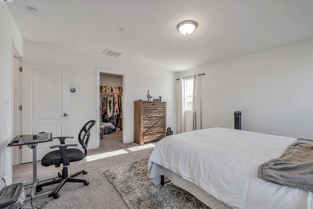 bedroom with a closet, a walk in closet, and carpet