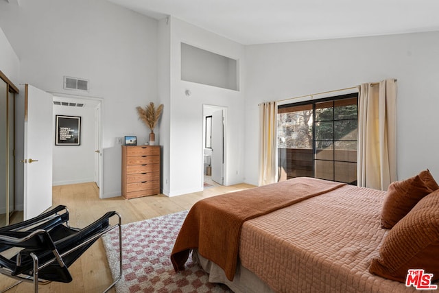 bedroom with a high ceiling and light wood-type flooring