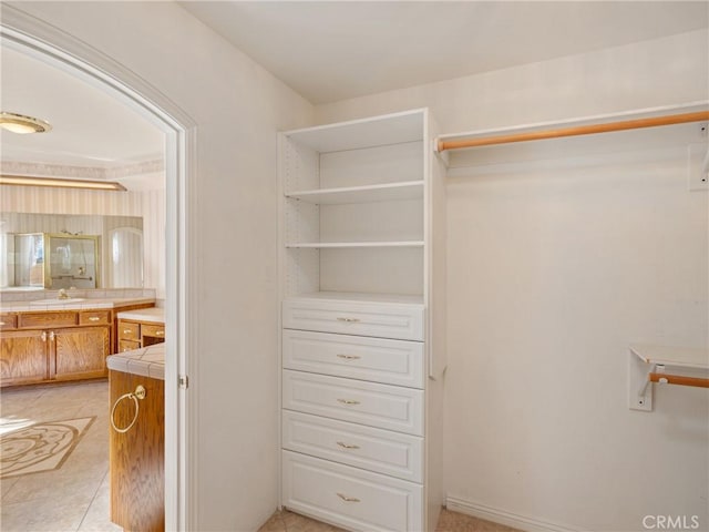 spacious closet featuring sink and light tile patterned flooring