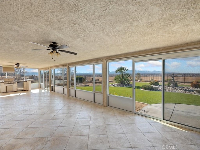 unfurnished sunroom with ceiling fan and plenty of natural light