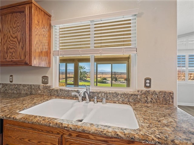 kitchen featuring plenty of natural light, light stone counters, and sink