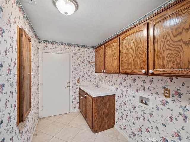 laundry area featuring cabinets, light tile patterned floors, sink, and hookup for a washing machine