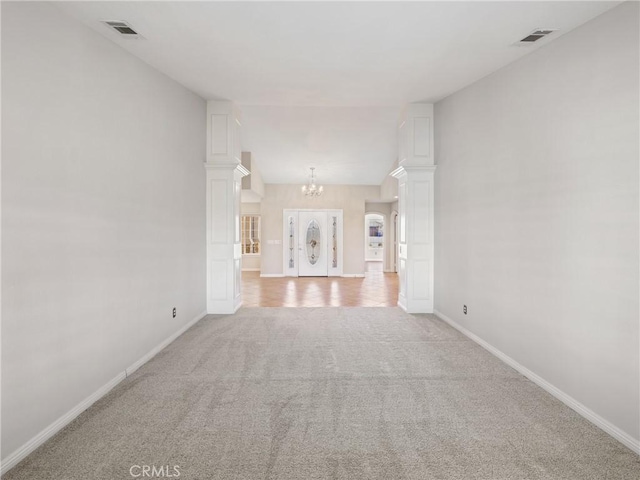 unfurnished living room featuring light colored carpet, vaulted ceiling, and an inviting chandelier