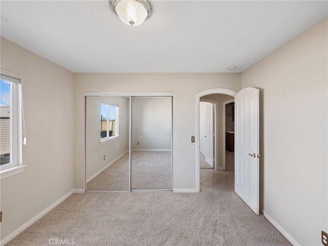 unfurnished bedroom featuring light colored carpet, multiple windows, and a closet