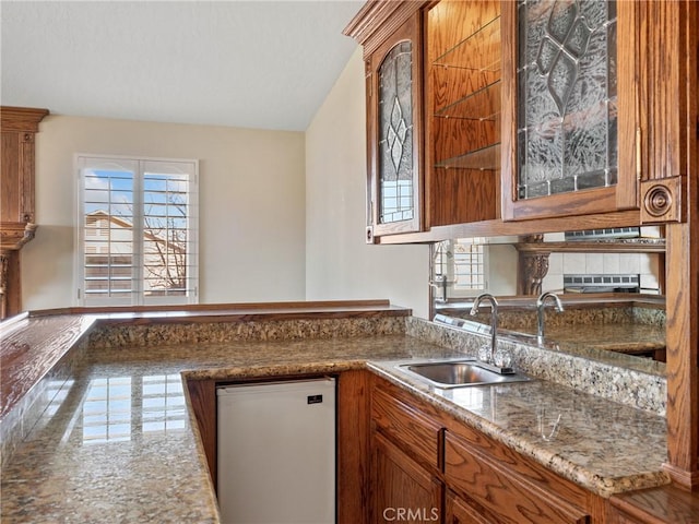 kitchen with dishwasher, sink, and light stone counters