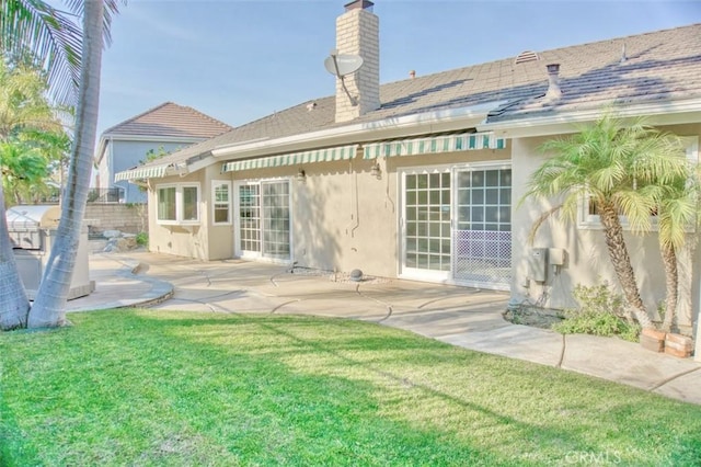 back of house with a lawn and a patio