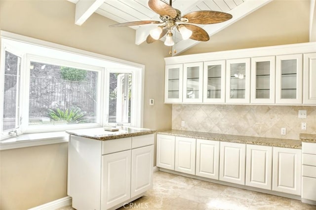 kitchen featuring light stone countertops, white cabinetry, vaulted ceiling with beams, tasteful backsplash, and ceiling fan