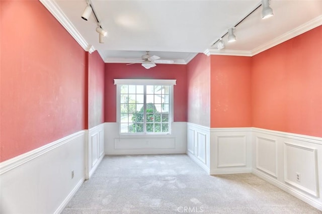 empty room with light carpet, ceiling fan, track lighting, and ornamental molding