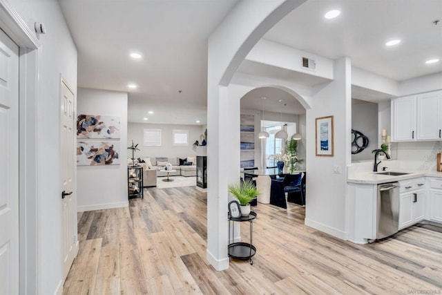 kitchen with sink, white cabinetry, dishwasher, and light hardwood / wood-style flooring