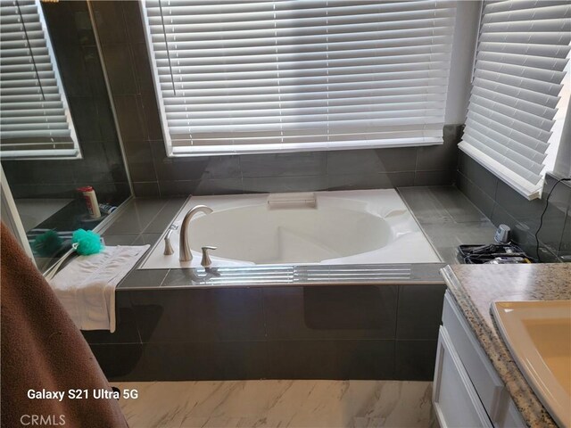 bathroom featuring vanity and a relaxing tiled tub