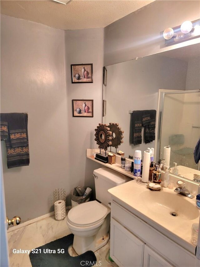 bathroom featuring vanity, walk in shower, a textured ceiling, and toilet