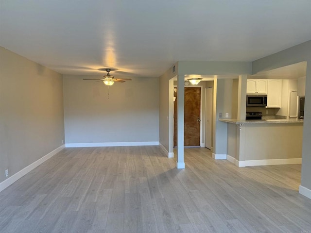 interior space with light hardwood / wood-style floors, kitchen peninsula, ceiling fan, appliances with stainless steel finishes, and white cabinets