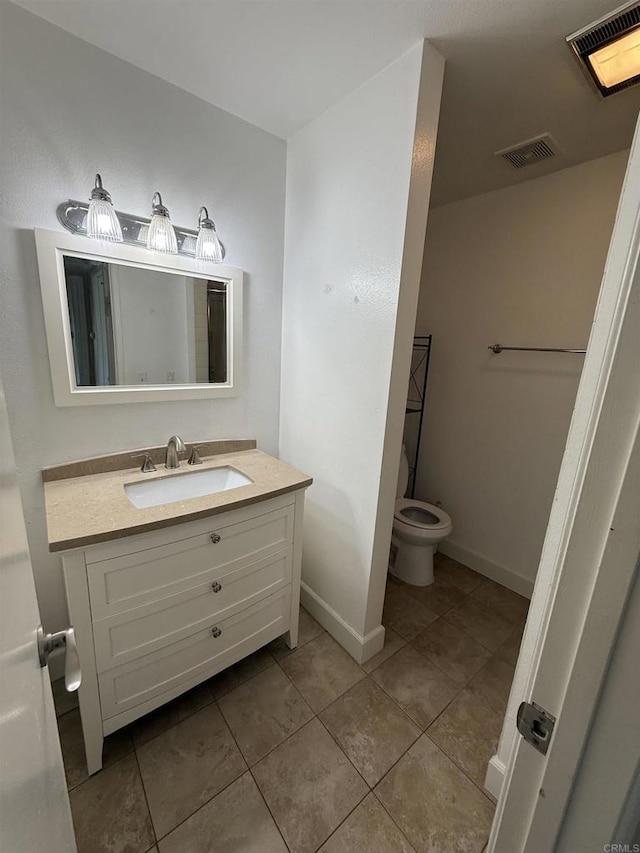 bathroom with toilet, vanity, and tile patterned flooring