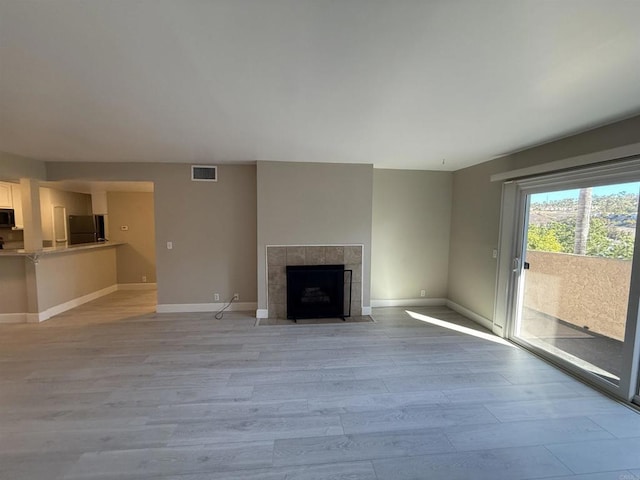 unfurnished living room featuring light hardwood / wood-style flooring and a tile fireplace