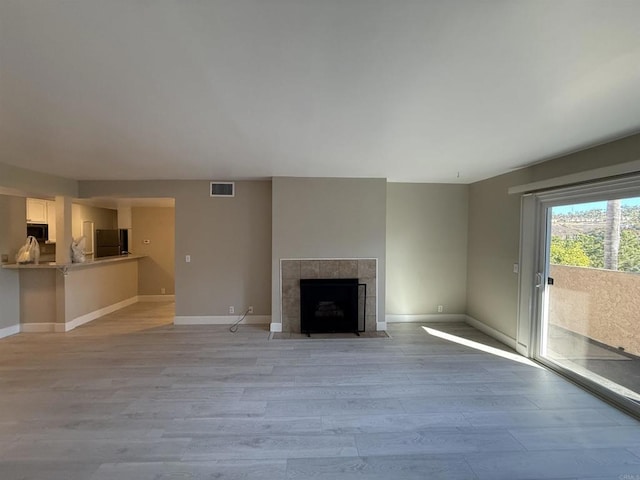 unfurnished living room featuring light wood-type flooring and a tile fireplace