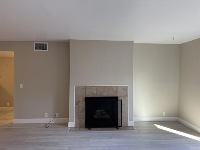 interior details featuring hardwood / wood-style flooring and a tiled fireplace