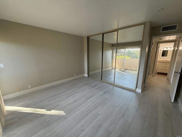 unfurnished bedroom featuring light hardwood / wood-style floors, access to exterior, and a closet