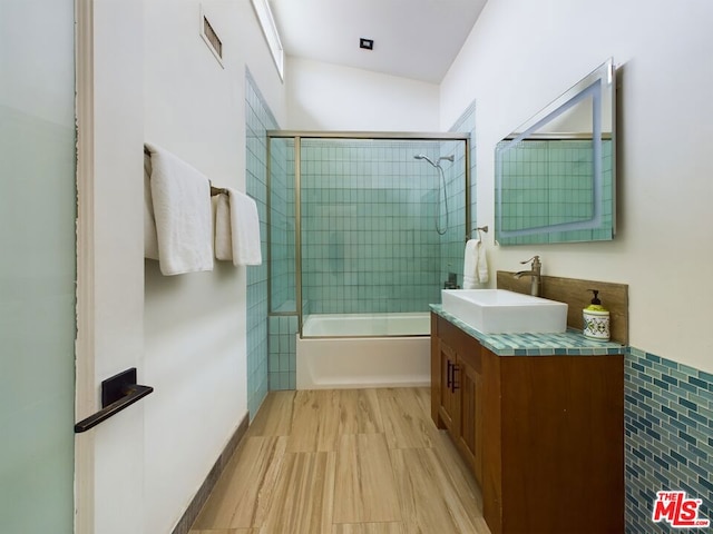 bathroom featuring combined bath / shower with glass door and vanity