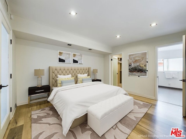 bedroom with light hardwood / wood-style floors, a walk in closet, and ensuite bath