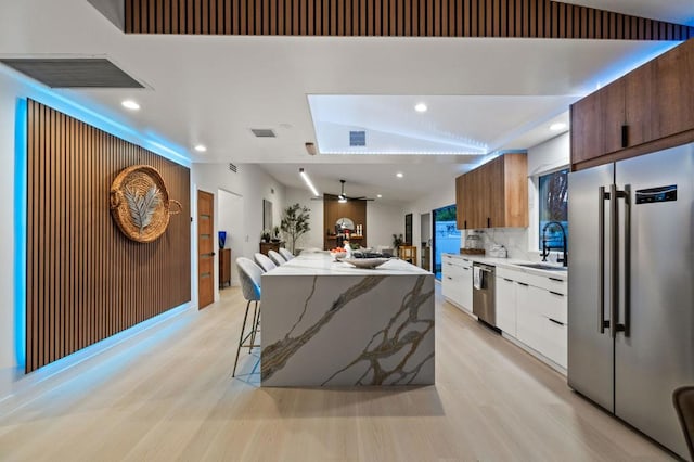 kitchen with a kitchen island, decorative backsplash, sink, white cabinetry, and appliances with stainless steel finishes