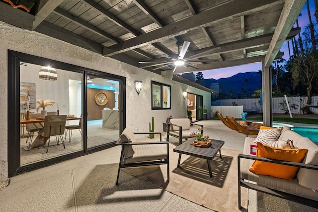 patio terrace at dusk featuring ceiling fan, a mountain view, and outdoor lounge area